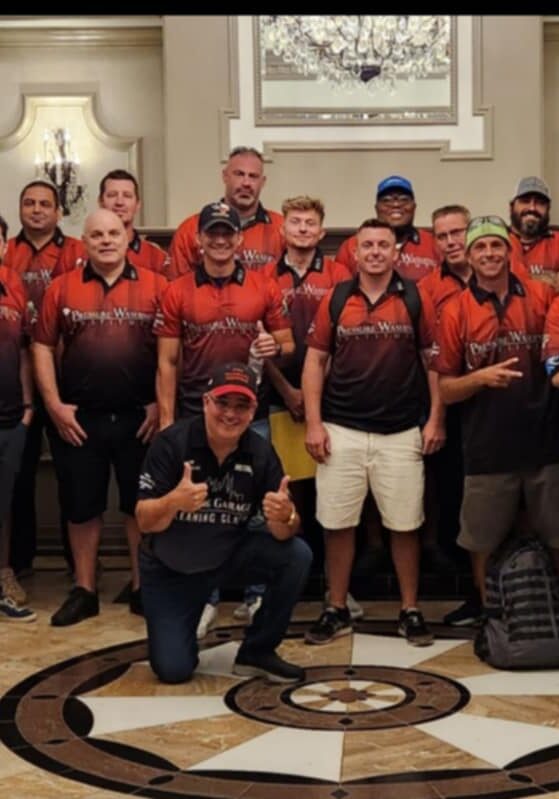 A large group of professionals wearing matching red and black branded shirts, standing together indoors for a team photo, promoting unity, teamwork, and their commitment to a Clean Country